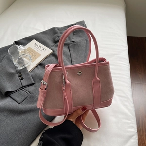 Detail of pink suede bucket bag featuring contrast leather handles and round metal buckle