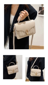 Detail of cream white leather bag showing golden oval twist lock and fine vertical stitching