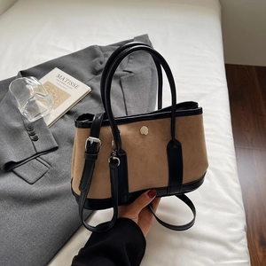 Close-up of contrast bucket bag with khaki suede texture and black leather handles