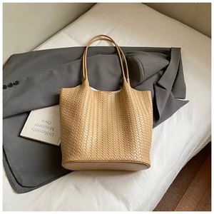 Detail of the high-capacity woven tote bag in tan showing texture and slim shoulder straps
