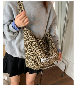 Detail of leopard print canvas tote bag featuring MUTING text and wide shoulder strap