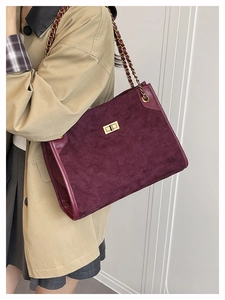Macro view of burgundy suede tote with quilted texture and gold chain strap