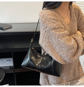 Close-up of black wrinkled patent leather shoulder bag showing glossy texture and details
