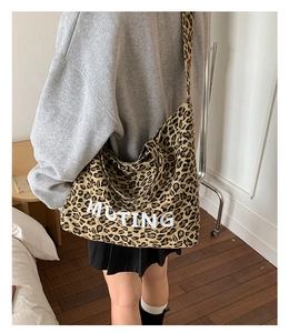 Detail view of large leopard print canvas tote bag with MUTING text being worn over the shoulder