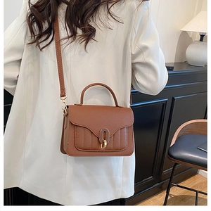 Detail of a brown leather shoulder bag with lychee texture and U-shaped golden metal clasp