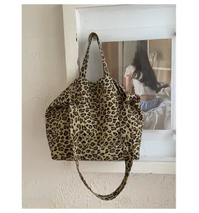 Detail of leopard print canvas tote bag with OUTING text hanging on a white wall