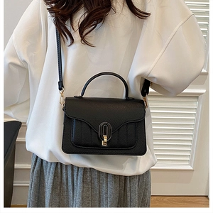 Detailed close-up of black lychee texture leather handbag with gold oval twist lock