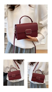Detail of dark red lychee leather crossbody bag with gold buckle and handle