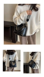 Detail of matte black bucket bag with geometric wide strap and leather texture