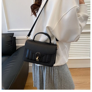 Detail of black lychee leather crossbody bag with gold U-shaped lock and quilted stitching