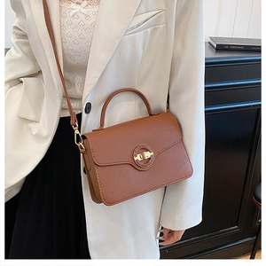 Détail d'un sac à main marron avec motif litchi et fermoir circulaire en métal doré