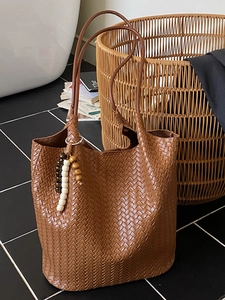 Brown woven tote bag with leather straps and decorative wooden beads in a retro style