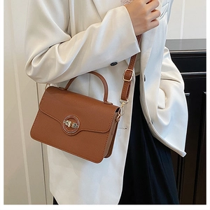 Sac à bandoulière en cuir marron avec boucle dorée sur une tenue de blazer blanc