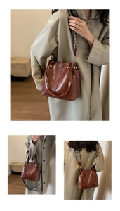 Detail view of brown bucket bag with decorative metal studs and woven shoulder strap