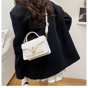 Detailed macro view of white lychee pattern leather crossbody bag with gold metal lock
