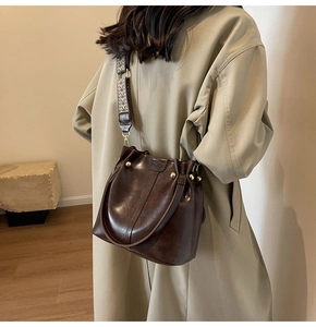 Detail of dark brown vintage bucket bag with ethnic woven strap and golden rivets