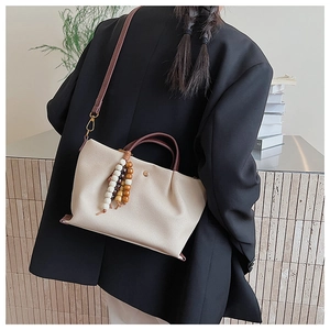 Chic cream canvas tote bag with brown leather handles and decorative wooden beads
