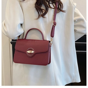 Détail d'un sac à main bordeaux en cuir grainé avec un fermoir rotatif doré élégant