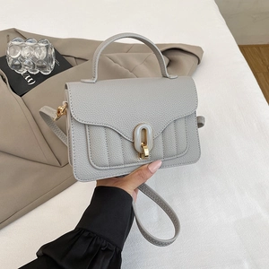 Detail of grey lychee leather crossbody bag featuring an elegant gold-tone enamel buckle