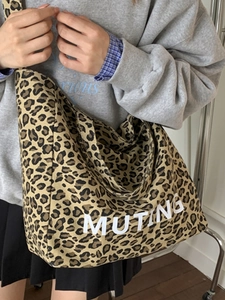 Large leopard print canvas tote bag with MUTING text being worn as a shoulder bag