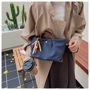 Blue canvas tote bag with brown leather straps and colorful bohemian bead tassel detail