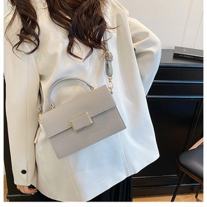 Detailed view of the grey textured leather texture and golden buckle on a stylish handbag