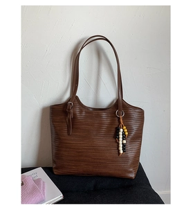 Détail d'un sac cabas marron tissé avec pampille de perles et bandoulière à boucle métallique