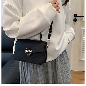 Gros plan d'un sac en cuir noir avec fermoir doré rotatif et bandoulière réglable en cuir souple