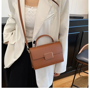 Detail of caramel brown leather square bag with gold metal buckle and pebble texture
