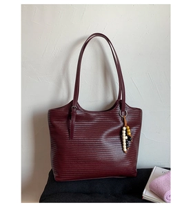 Détail du sac cabas tissé bordeaux montrant la texture entrelacée et le charme en bois