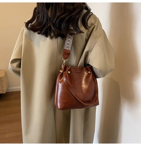 Detail view of brown vintage bucket bag with ethnic geometric strap and golden studs