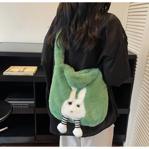 Detail of green plush shoulder bag with cute rabbit pendant shown on model's shoulder