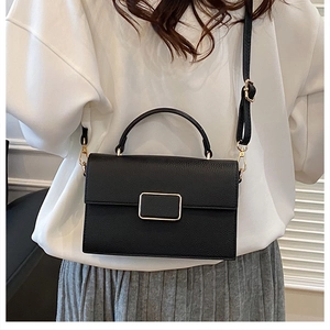 Detail of black lychee texture leather crossbody bag with gold buckle and top handle