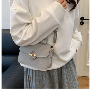 Détail du sac bandoulière en cuir grainé gris clair avec fermoir rotatif doré