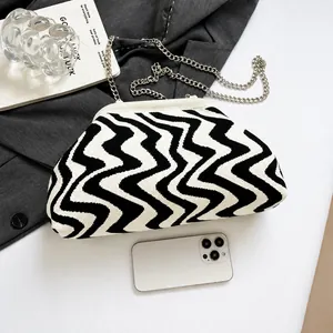Close-up of wavy knit texture and silver chain strap on the monochrome crossbody bag
