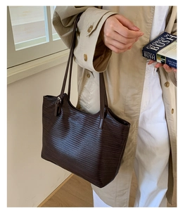 Détail d'un sac cabas marron foncé texturé porté par un mannequin pour le quotidien
