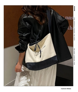Detail of canvas tote bag with drawstring bow and contrasting cream and navy blue panels