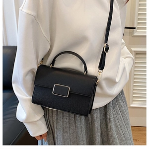 Detail of black lychee grain handbag featuring a gold buckle and adjustable strap