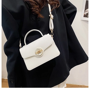 Sac carré chic en cuir grainé blanc avec fermoir doré sur une veste noire