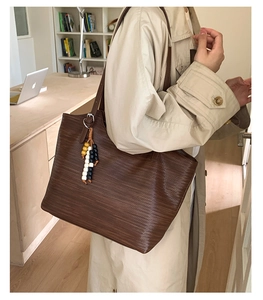 Détail du sac cabas marron foncé avec texture tressée et accessoire de charme en perles
