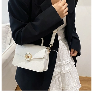 Détail de sac à main en cuir grainé blanc avec fermoir rotatif doré circulaire