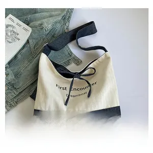 Detail of canvas tote bag showing blue denim patchwork, bow tie, and stylish text print