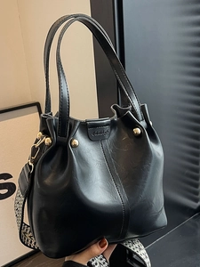 Chic black bucket bag in retro leather style with a patterned woven shoulder strap