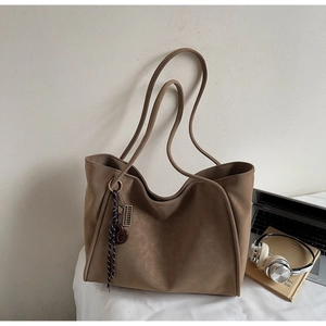 Detail of vintage brown tote bag with checkered scarf charm and office accessories