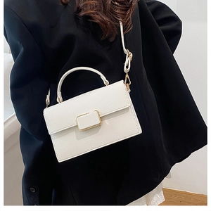 Close-up of white pebbled leather handbag with gold buckle and elegant top handle