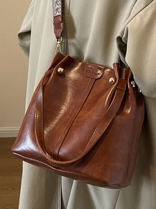 Vintage brown leather bucket bag with retro patterned wide strap and gold metal rivets