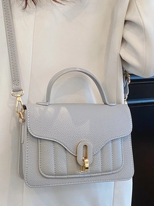 Chic grey leather crossbody bag with gold hardware and vertical quilting details