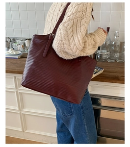 Vue détaillée du sac cabas bordeaux avec texture tressée et bandoulière réglable