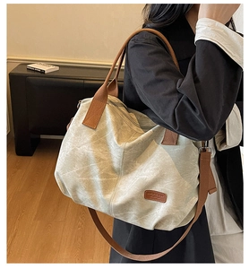 Detail of vintage canvas tote bag with brown straps and leather patch on model