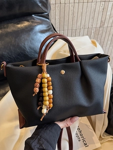 Minimalist black nylon tote bag with brown PU leather handles and colorful wood bead charm